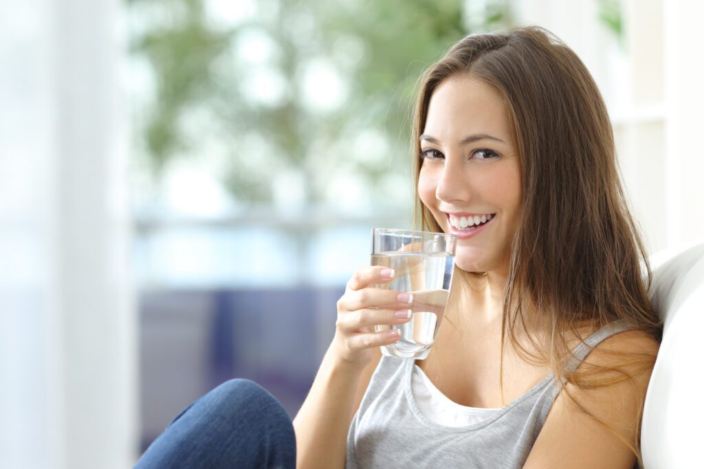 Jeune femme en jeûne qui boit un verre d'eau